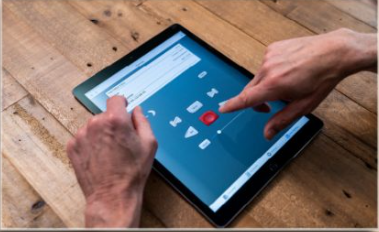 A man listens to a recording on a tablet as an accessibility features provided at the Library.