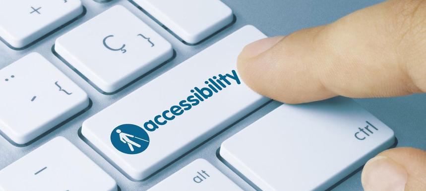 A person's index finger presses the accessibility blue icon on a keyboard.