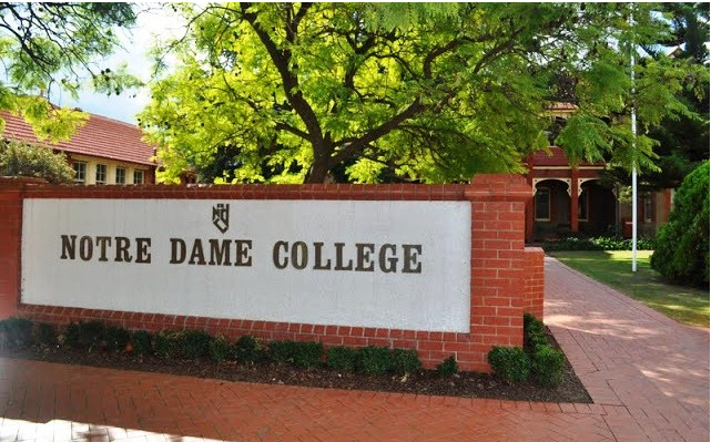 Notre Dame College campus sign on a red brick wall inside the campus.
