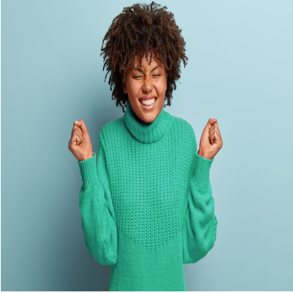 Lack of alt text for images in e-commerce business. The image shows a woman in a green knit sweater clutching her hands at the sides and smiling widely.