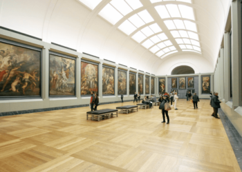 Visitors to a museum view the art exhibits in a vast gallery.