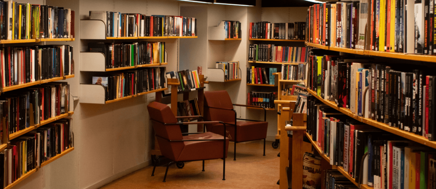 A dimly lit library space with various publishers books arranged on the shelves.